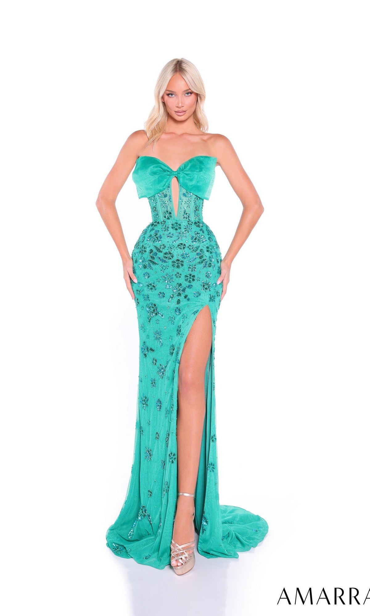 A woman wearing the Amarra 89079 long prom dress in teal, featuring a strapless fitted bodice, high slit, and floral embellishments, stands against a white background.